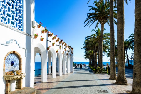 White building at Balcón de Europa in Nerja, Spain, surrounded by palm trees and overlooking the Mediterranean Sea