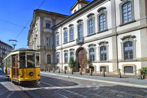 A historic palace with elegant architecture alongside a classic streetcar in Milan, Italy