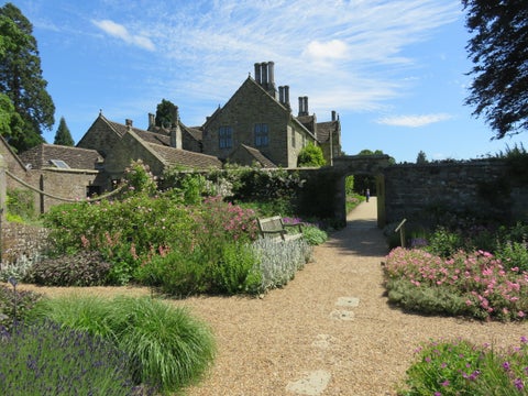 Row of traditional English houses featuring brick and timber facades, surrounded by well-maintained, colourful gardens in the village of Ardingly