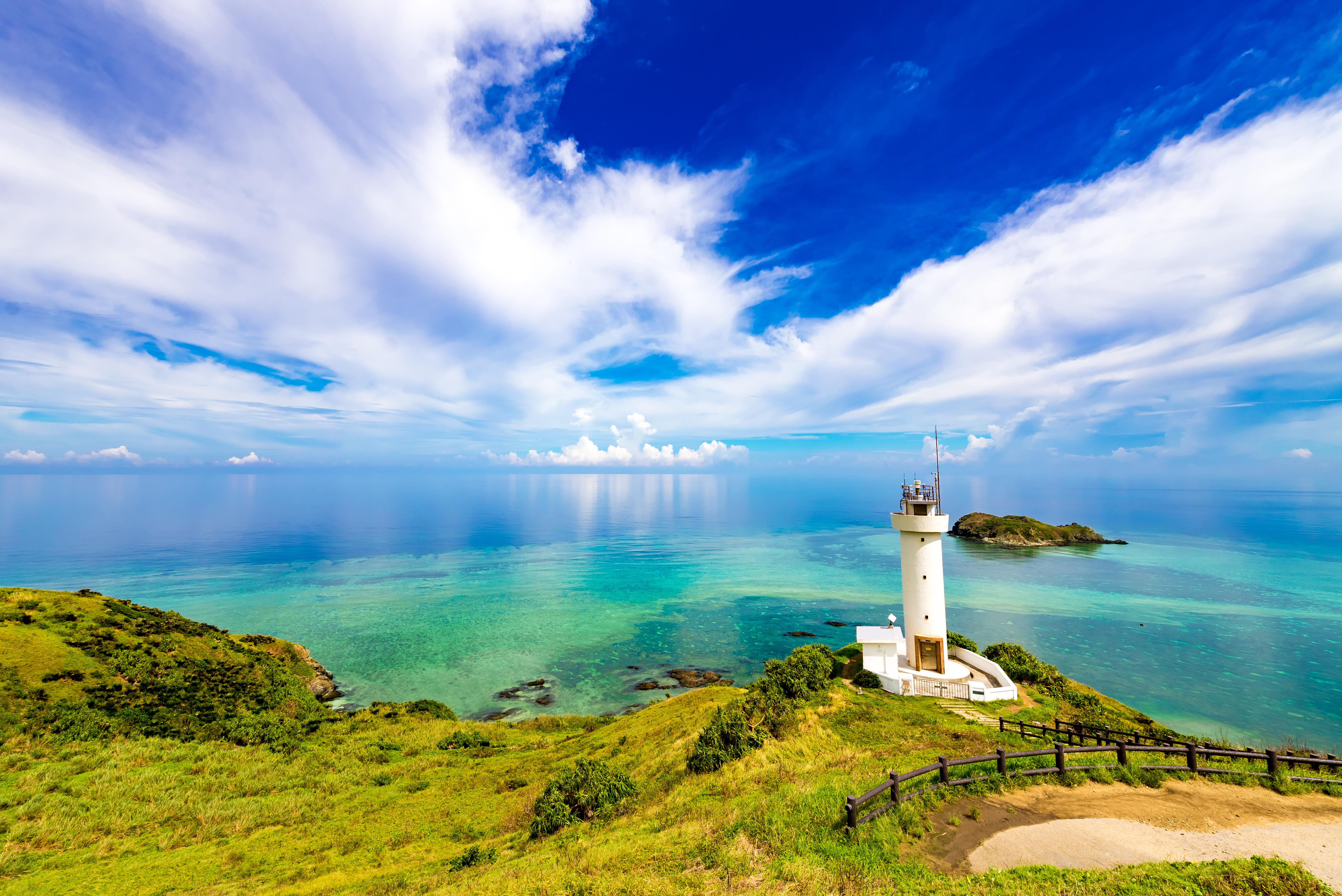 Scenic lighthouse overlooking a pristine sandy beach and clear blue sea in Okinawa, Japan