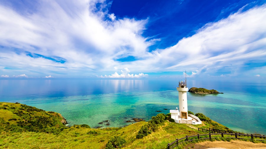 Scenic lighthouse overlooking a pristine sandy beach and clear blue sea in Okinawa, Japan