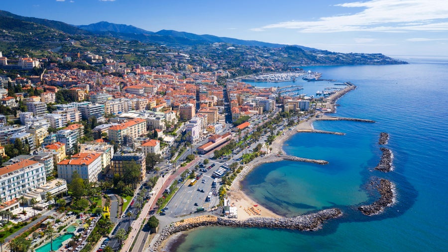 Aerial view of Sanremo, Italy, showing the coastline, hillside buildings, and Mediterranean Sea