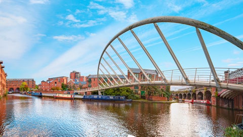Narrowboat on a canal with a modern bridge in Castlefield, Manchester, UK