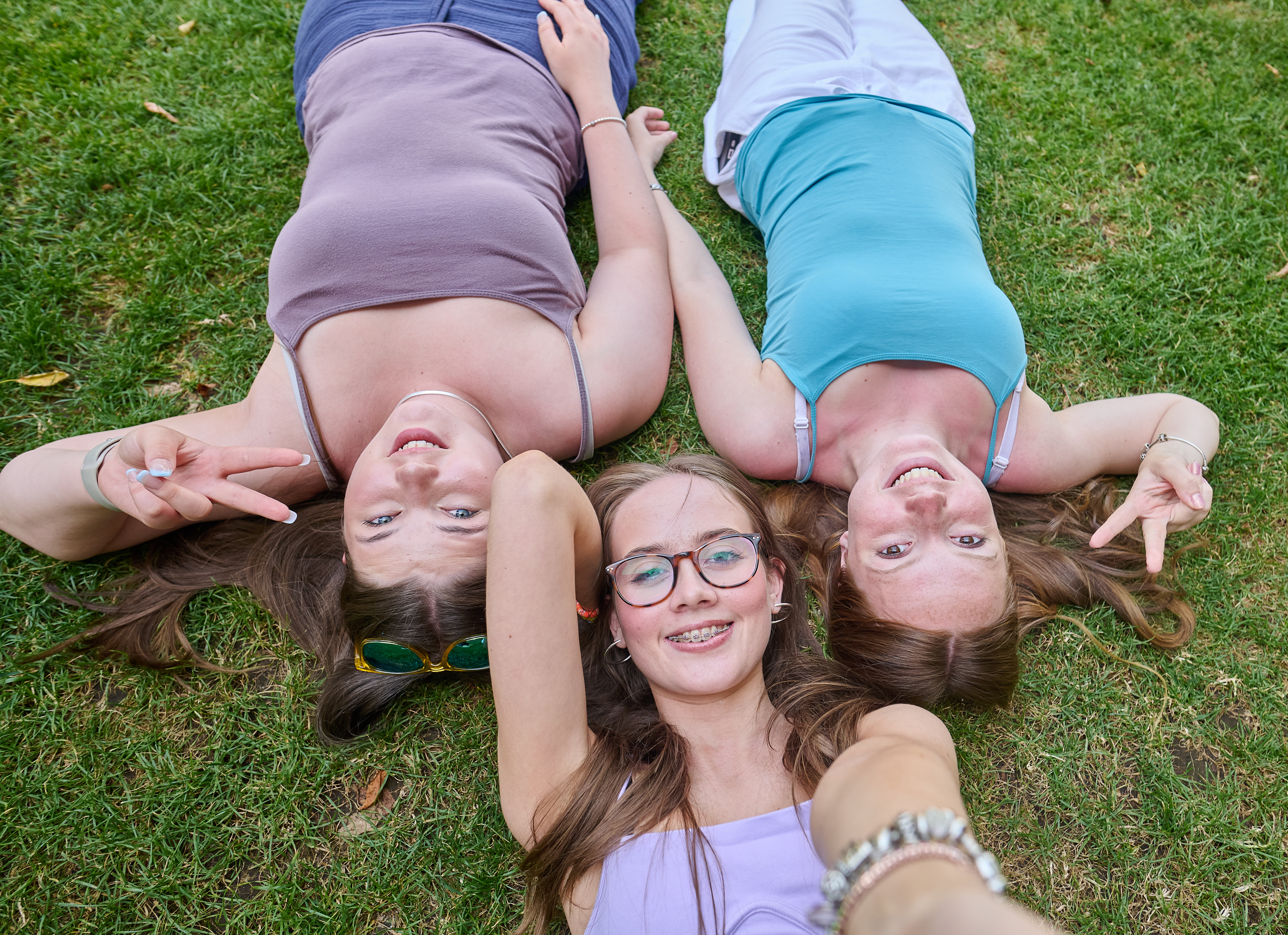 ESL teen students laying on the grass near London Tower Bridge smiling and posing for a sunny group photo