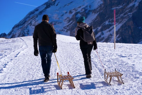 People enjoying snow activities in Engelberg, Switzerland, including skiing and snowboarding against a backdrop of alpine mountains