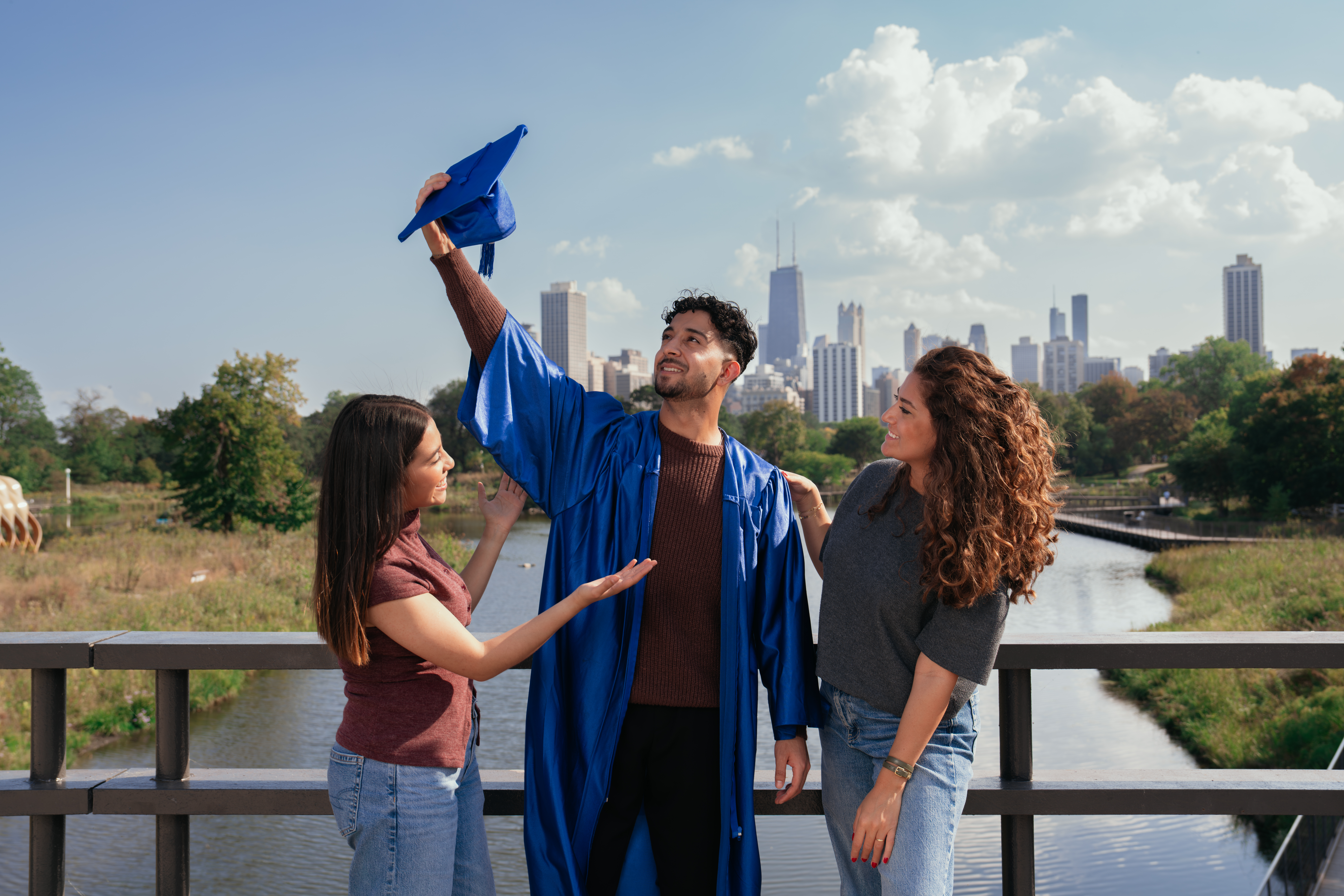 International students in a Chicago park by Lake Michigan, one wearing a graduation gown
