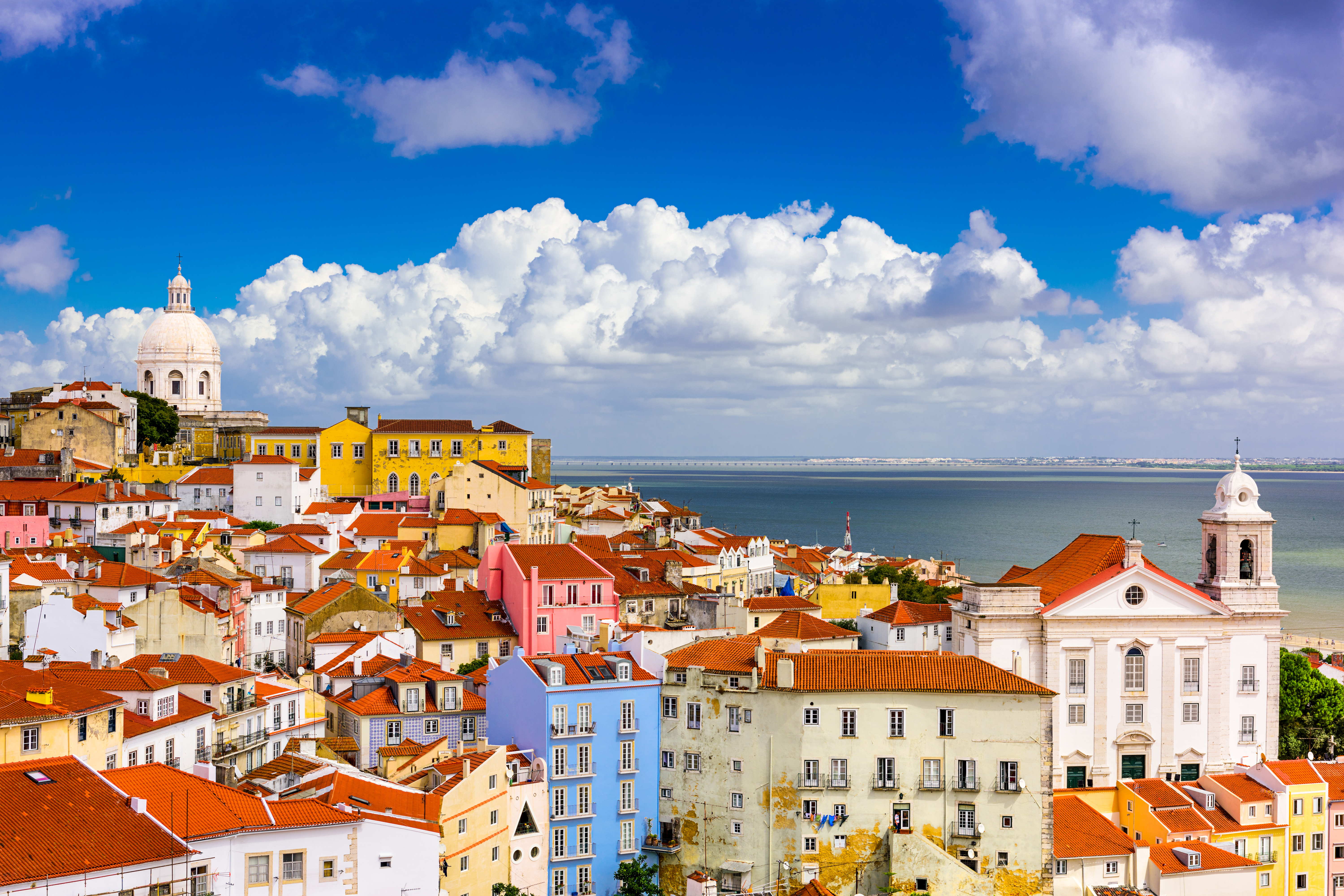 Aerial view of Alfama district in Lisbon with terracotta roofs, Lisbon Cathedral, São Jorge Castle, and the Tagus River in the background