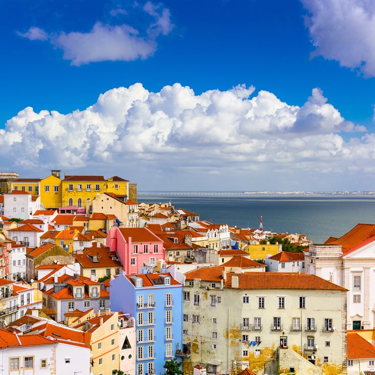 Aerial view of Alfama district in Lisbon with terracotta roofs, Lisbon Cathedral, São Jorge Castle, and the Tagus River in the background