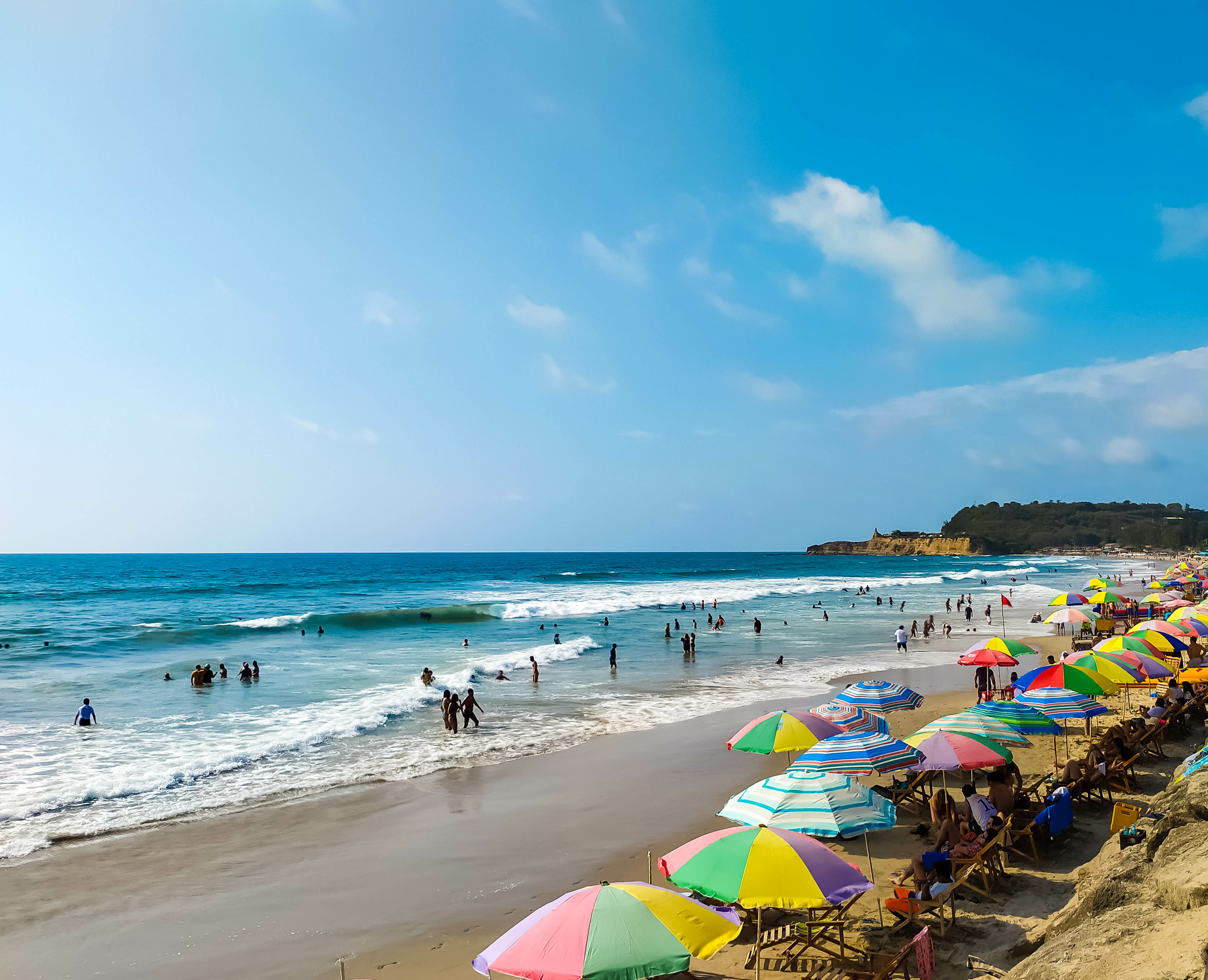 White-sand beach with colourful umbrellas and blue ocean in Montañita, Ecuador