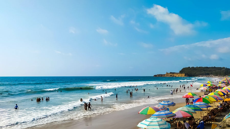 White-sand beach with colourful umbrellas and blue ocean in Montañita, Ecuador