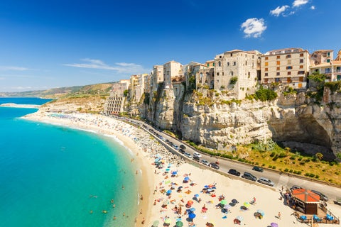 Aerial view of Tropea, Italy, showcasing the seaside cliffs, turquoise waters, and historic buildings perched above the beach