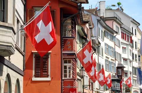 Swiss flags flying among historic buildings in the city center of Zurich, Switzerland