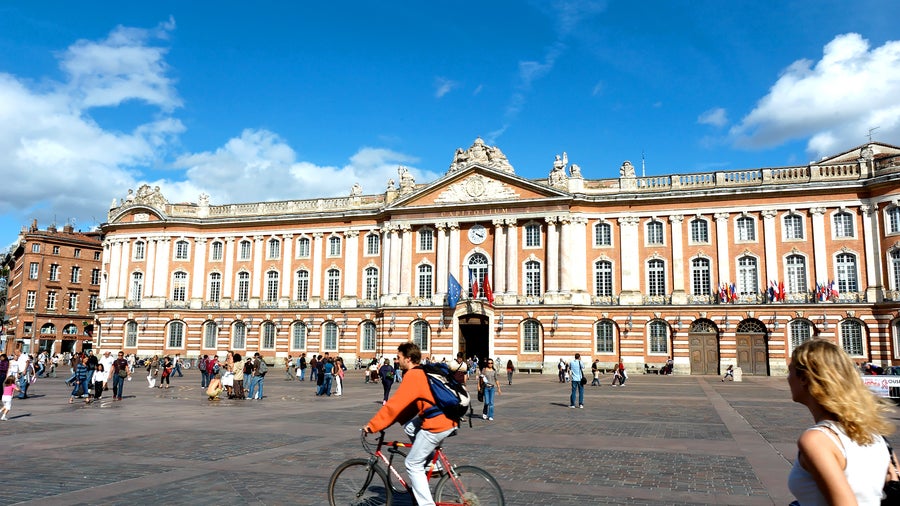 La Place du Capitole in Toulouse with its grand square framed by elegant pink-brick buildings, including the iconic Capitole de Toulouse