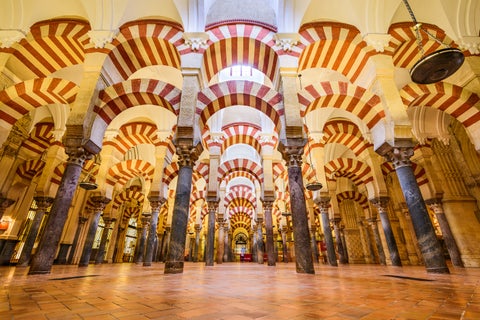 Interior of the Mezquita-Catedral de Córdoba featuring iconic white and red striped horseshoe arches