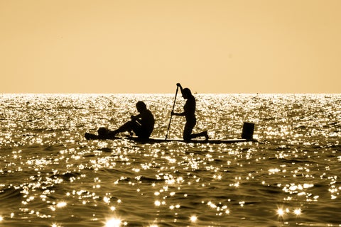 Tourists stand-up paddleboarding on the water in Málaga, Spain