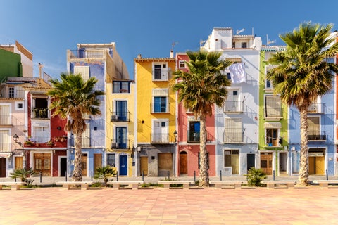 Colourful waterfront houses with palm trees near the beach in Alicante, Spain, capturing the vibrant coastal charm of the Mediterranean setting