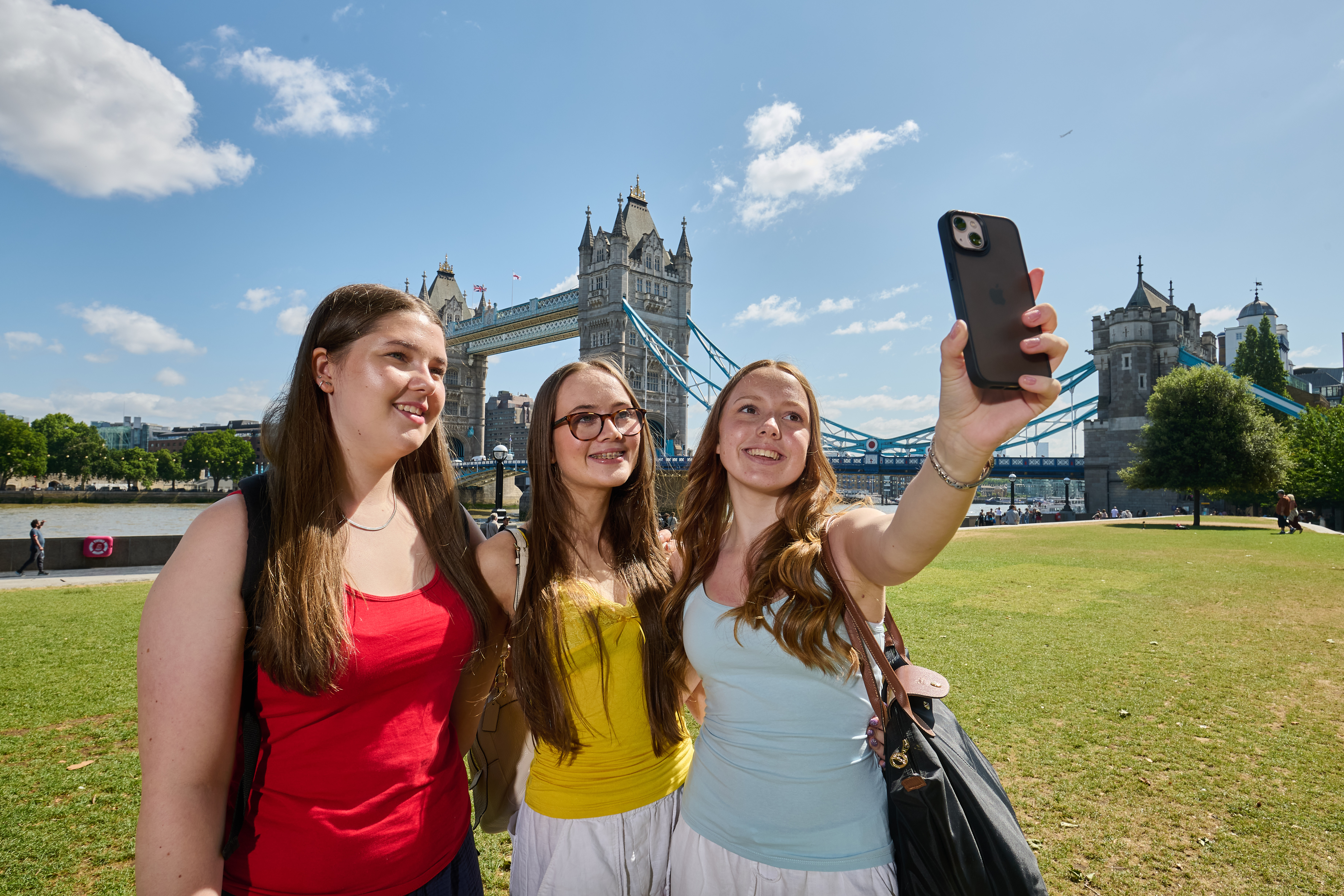 Three teen ESL students posing with Tower Bridge in London, England