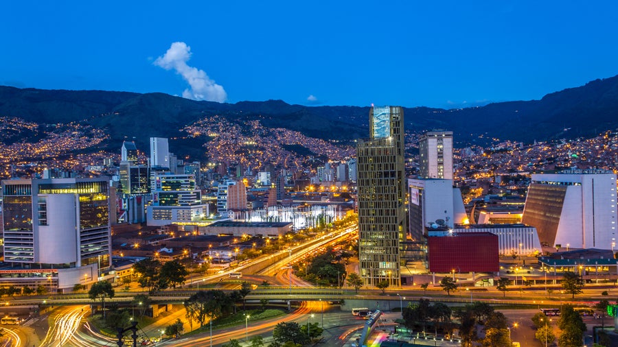 An aerial night view of Medellín City, Antioquia, Colombia, showing a dazzling urban landscape illuminated by countless city lights