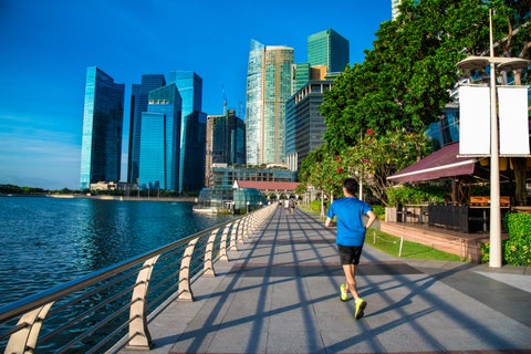 Runner at Singapore River waterfront with modern skyscrapers in the background