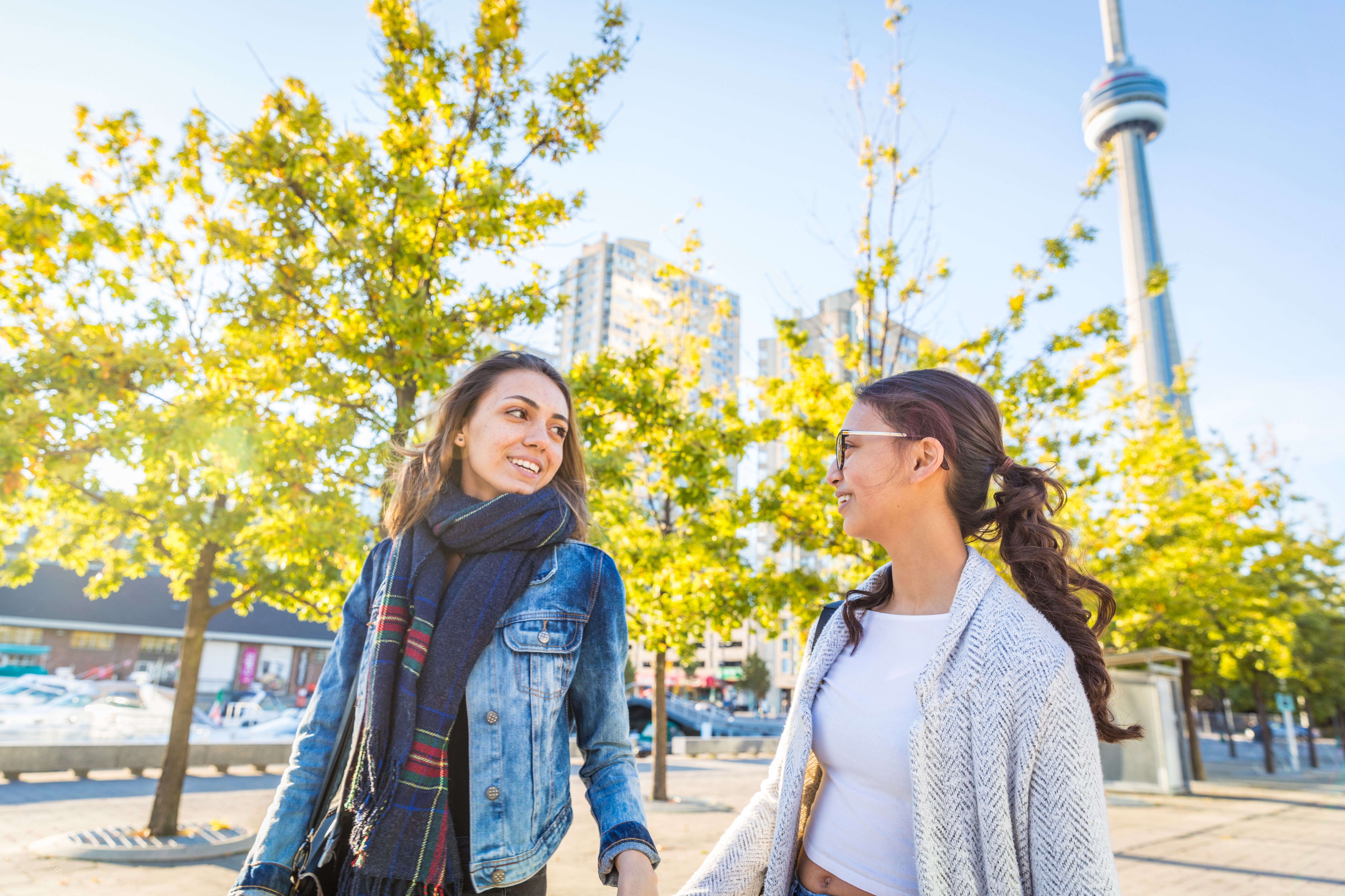 Students walking in Toronto city center with CN Tower in the background during spring, Canada