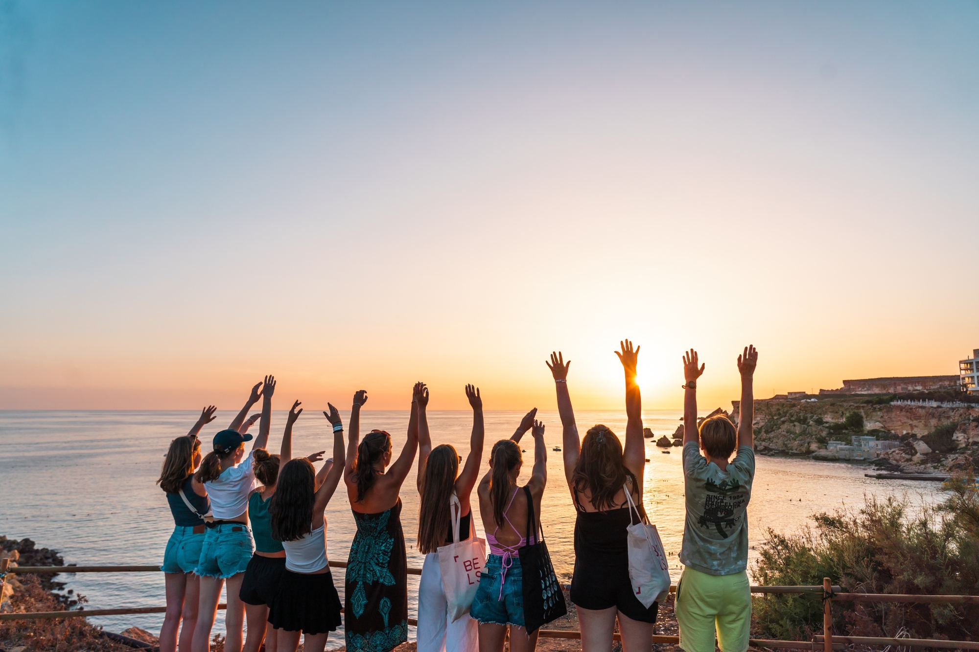 Students posing raising hands at sunset