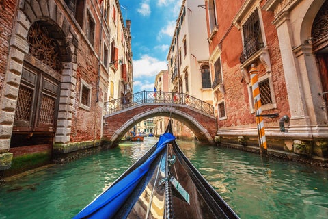 A boat navigating a narrow canal in Venice, Italy