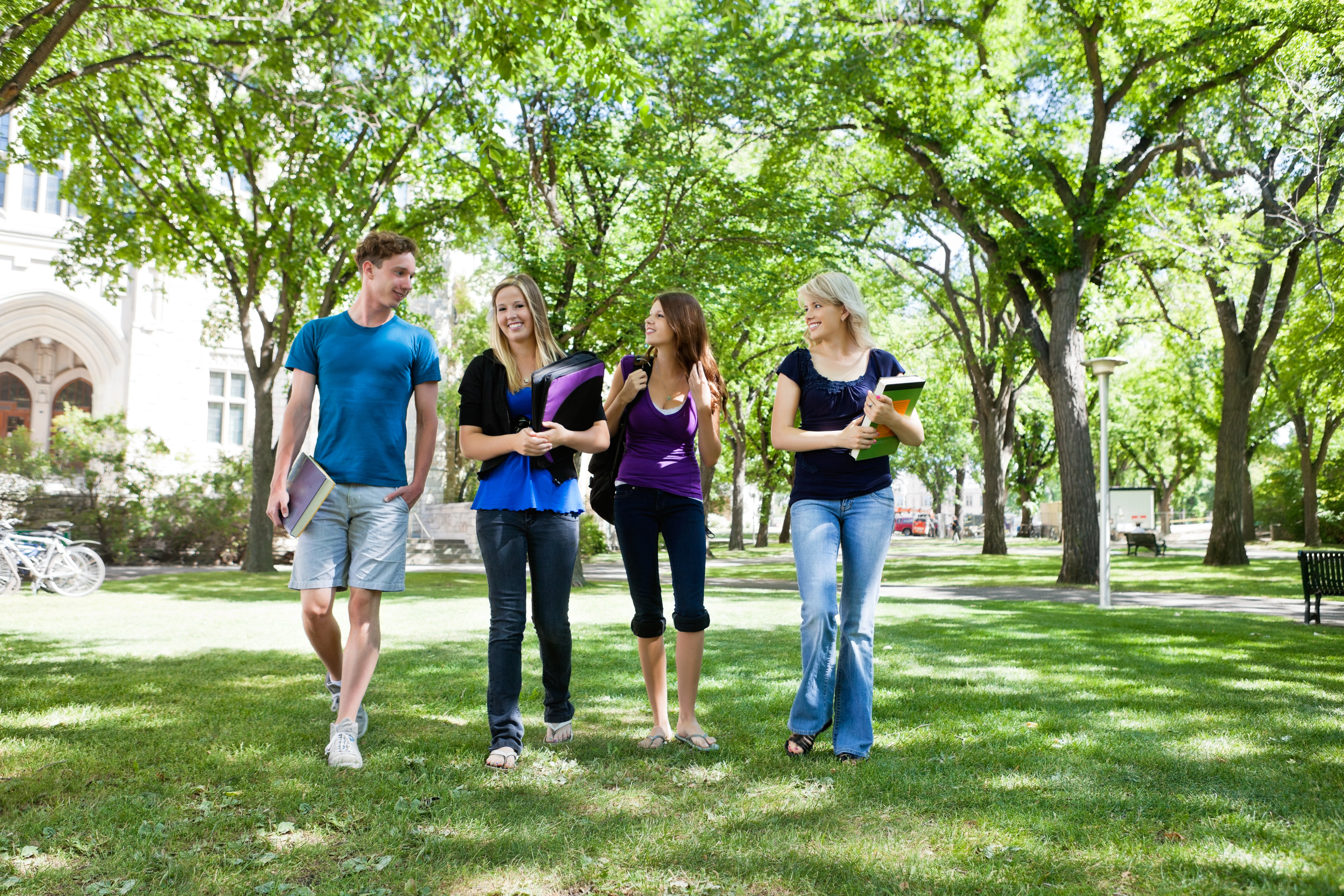 Students enjoying a walk on campus lawn with books in hand