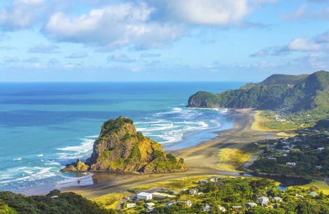 Scenic view of Lion Rock at Piha Beach, Auckland, New Zealand, with waves and rugged coastline in the background