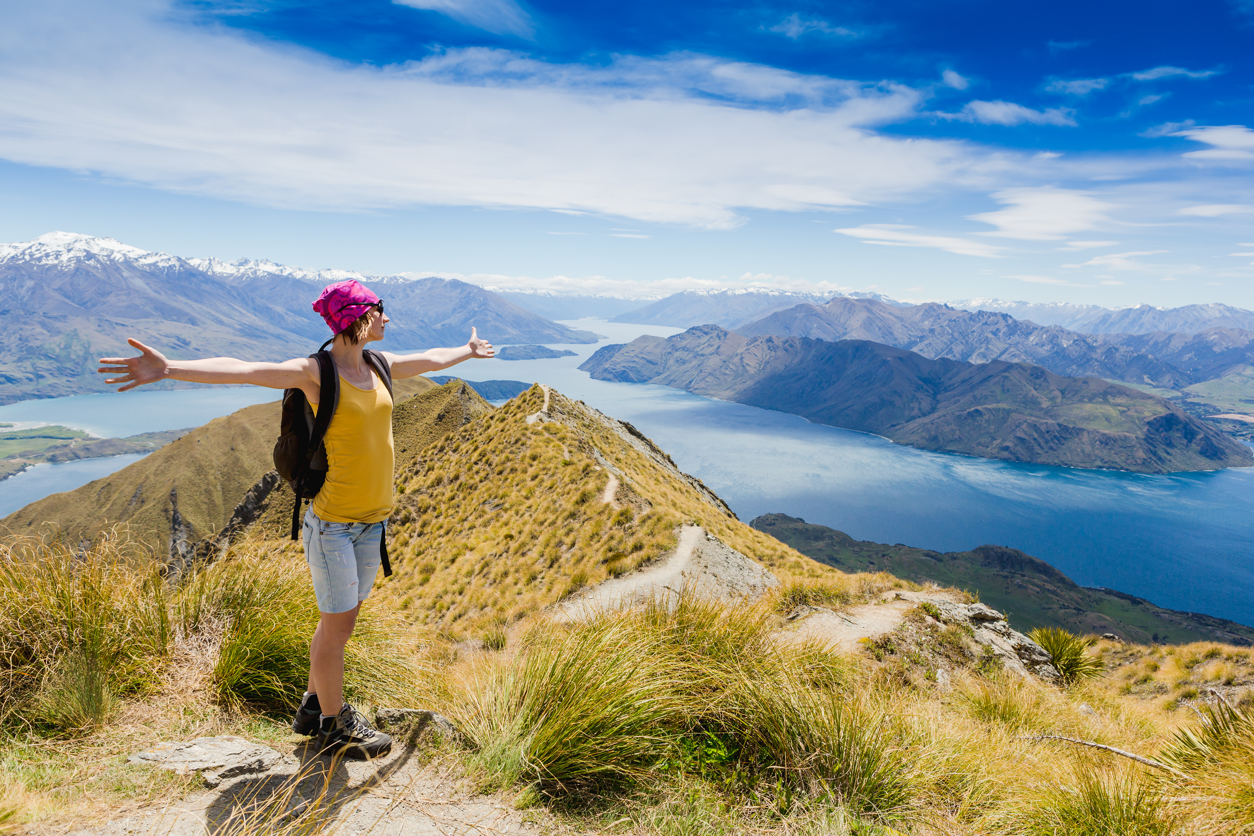 Hiker on Roy’s Peak ridge overlooking Lake Wanaka and Southern Alps in New Zealand