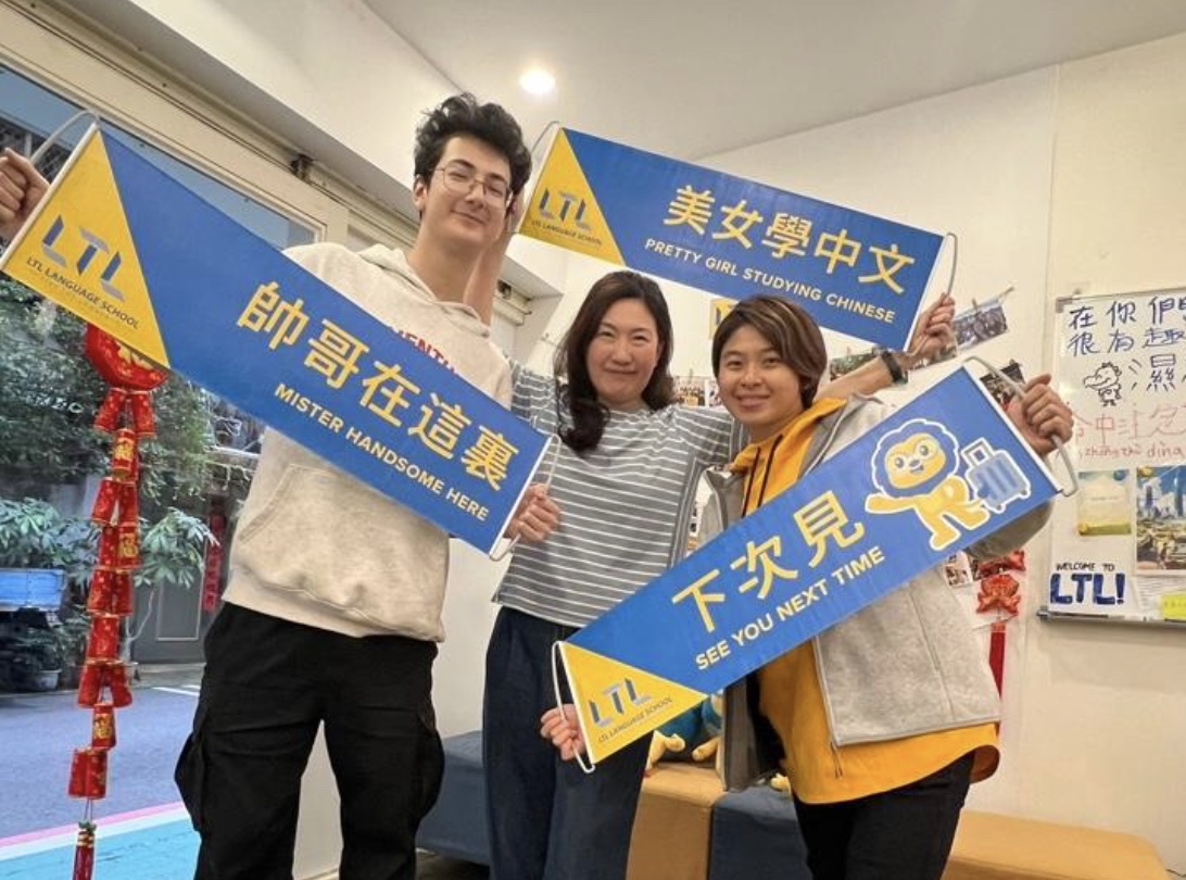 Three students holding banners at LTL Taipei