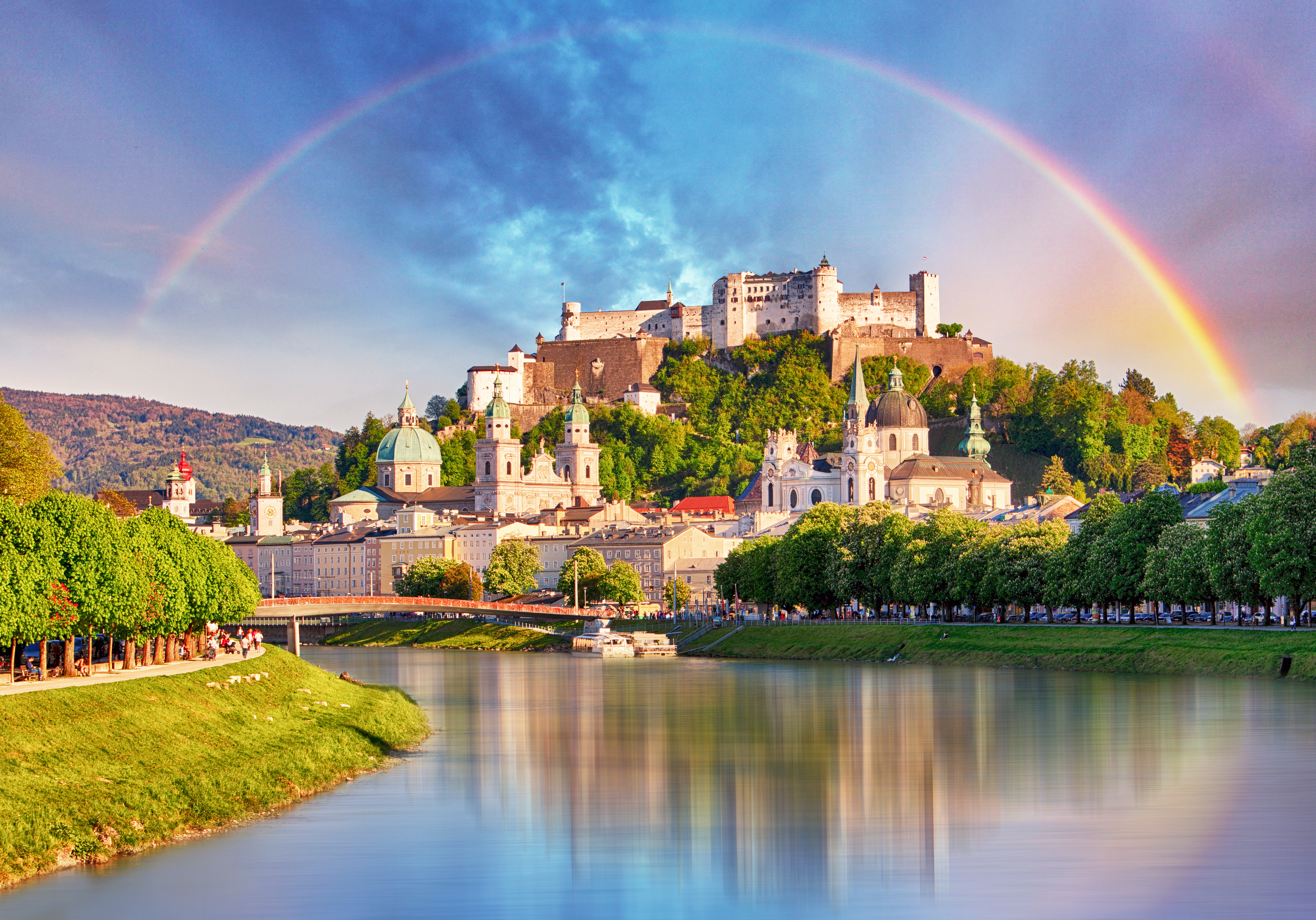A rainbow arching gracefully over the iconic Hohensalzburg Fortres in Salzburg, Austria