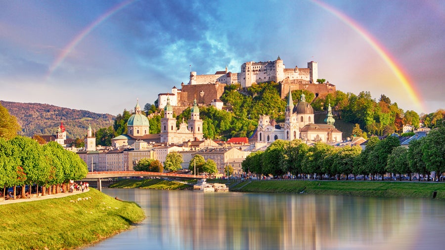 A rainbow arching gracefully over the iconic Hohensalzburg Fortres in Salzburg, Austria