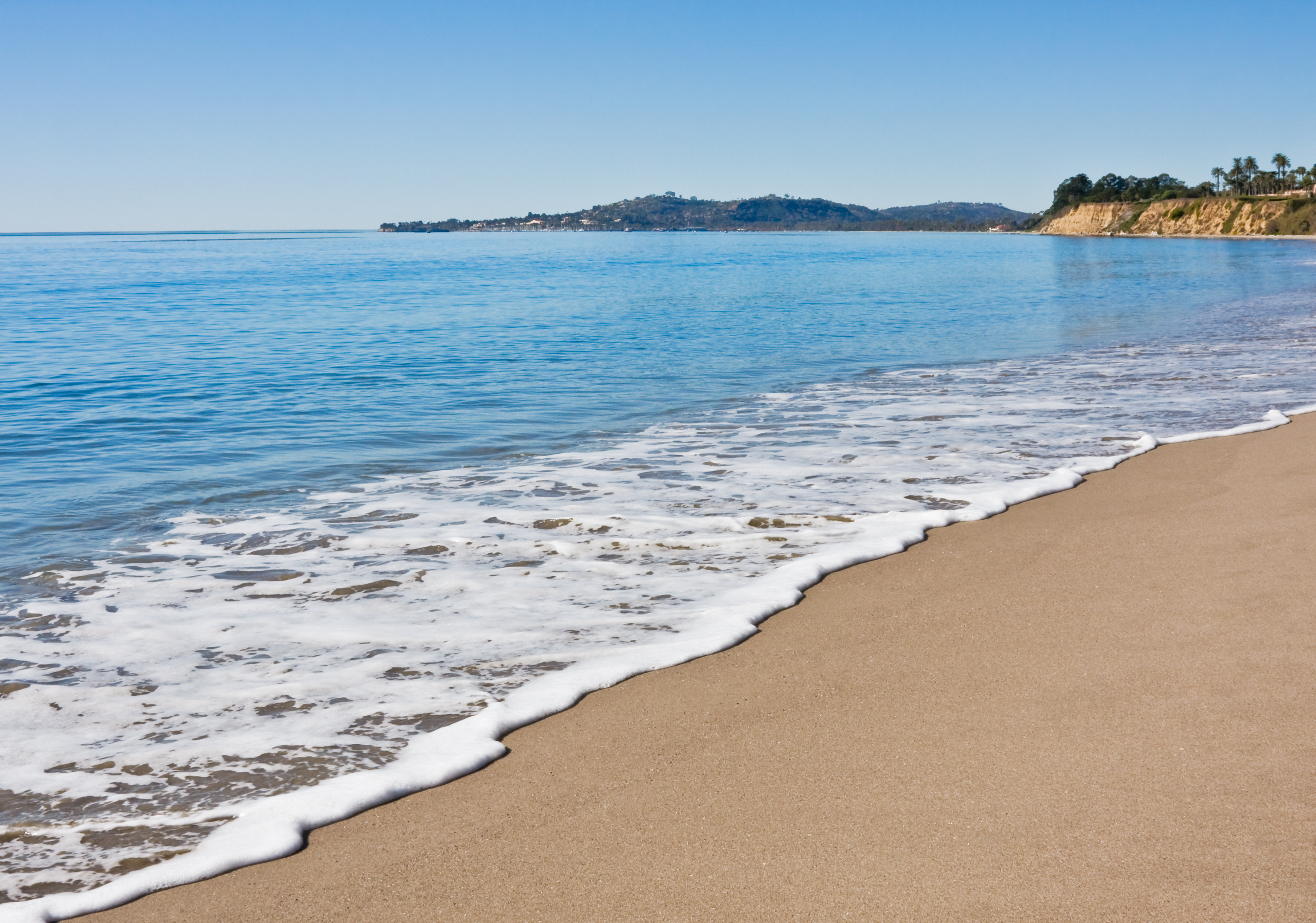 White-sand beach in Santa Barbara, California with waves and sunlit coastline