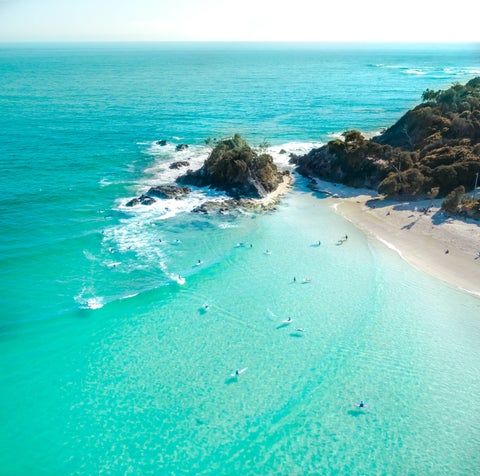 Aerial view of Byron Bay surrounded by lush greenery and overlooking the turquoise waters of the Pacific Ocean
