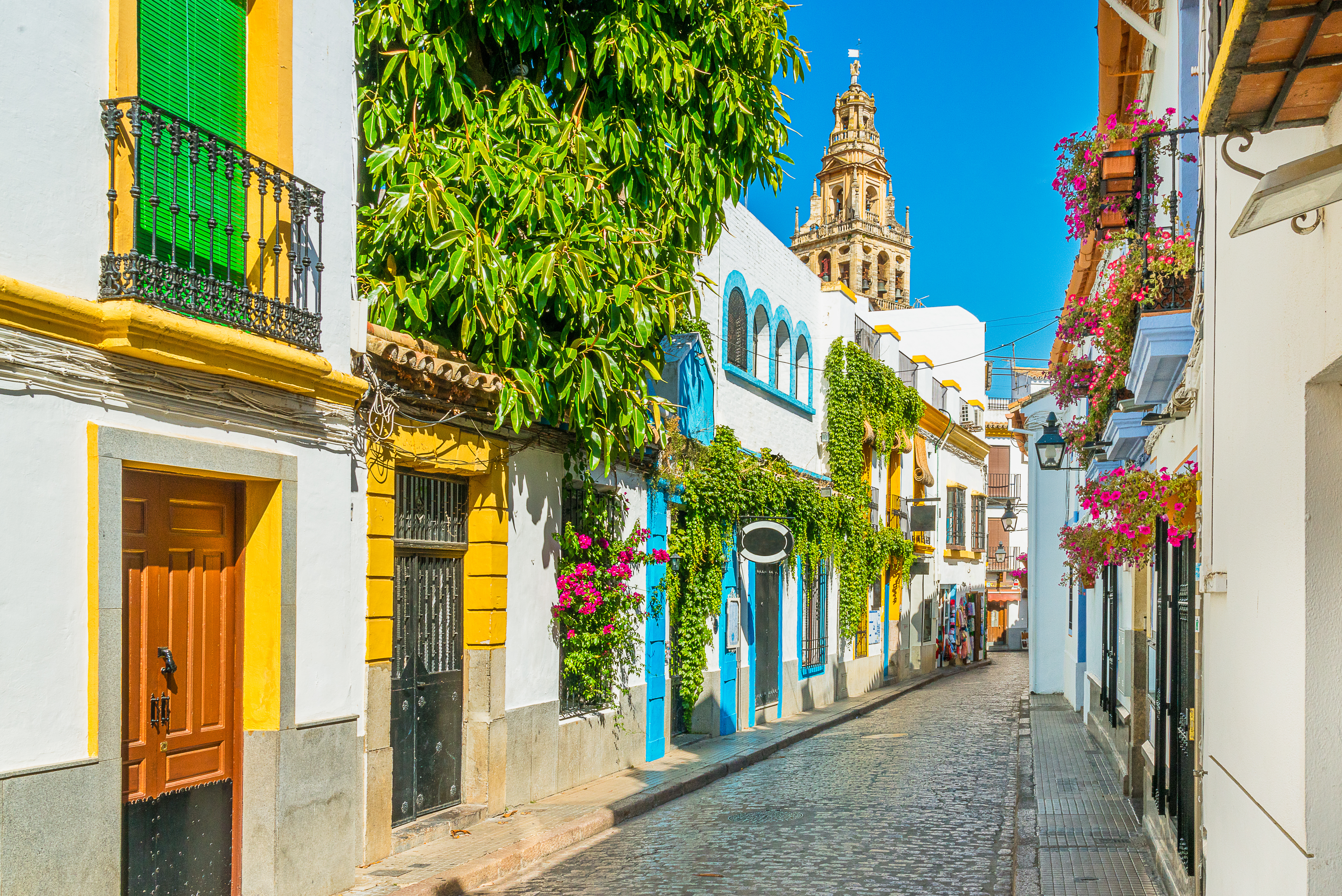 City center of Córdoba, Spain with white houses featuring colorful windows and doors, and the Torre de la Calahorra historic tower in the background