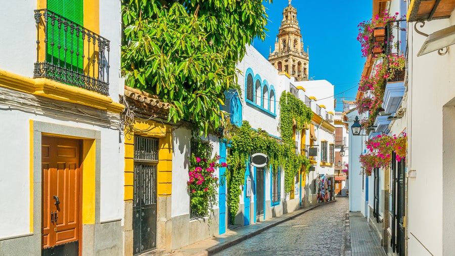 City center of Córdoba, Spain with white houses featuring colorful windows and doors, and the Torre de la Calahorra historic tower in the background