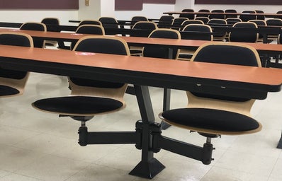tables with attached chairs, light wash with black cushions, in a classroom
