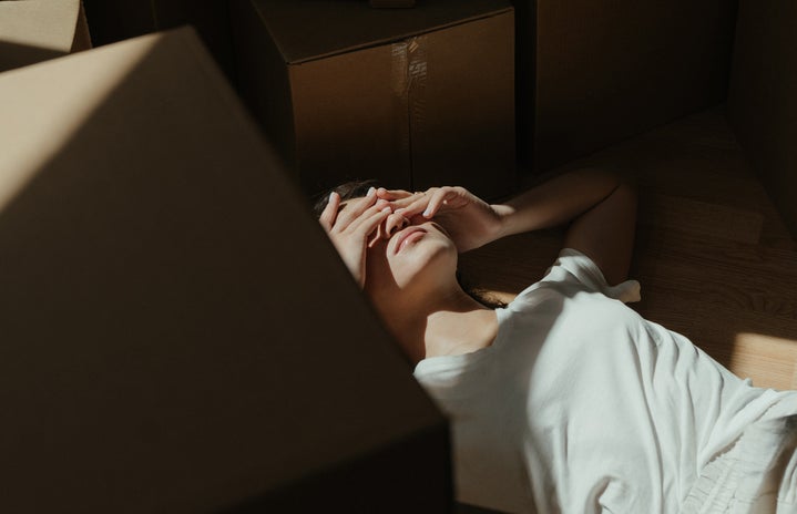 sad young woman laying by boxes