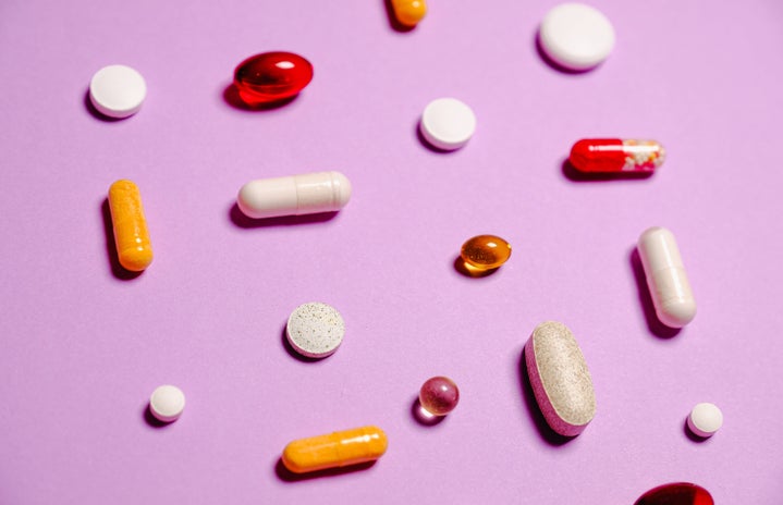 Vitamins laying on a pink background