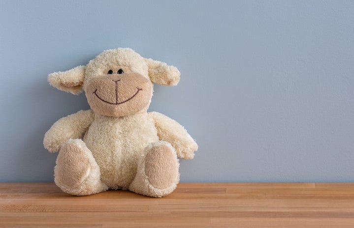 a white sheep plush toy sitting on the floor