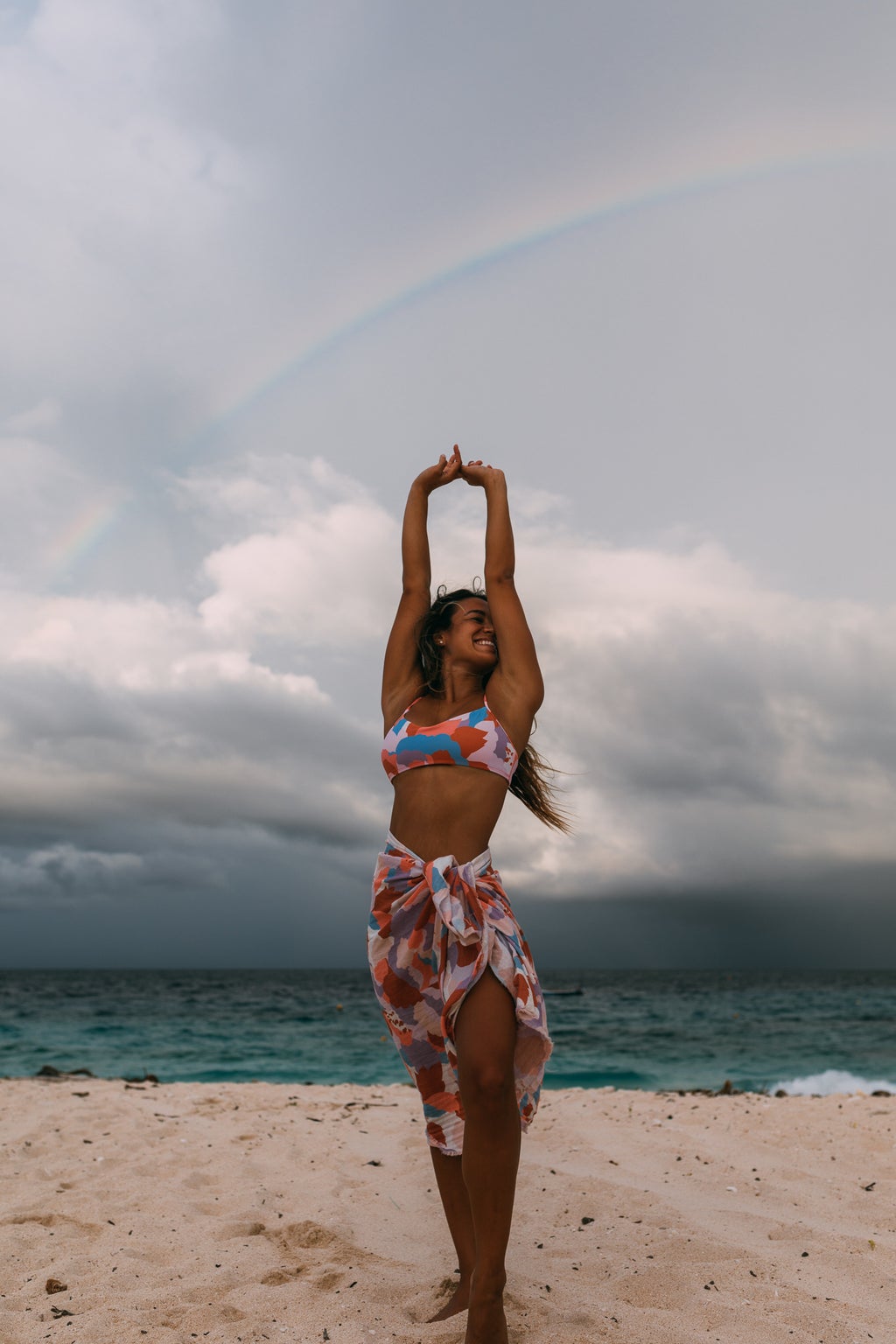 Influencer Eryn Krouse standing on the beach with a rainbow in the background.