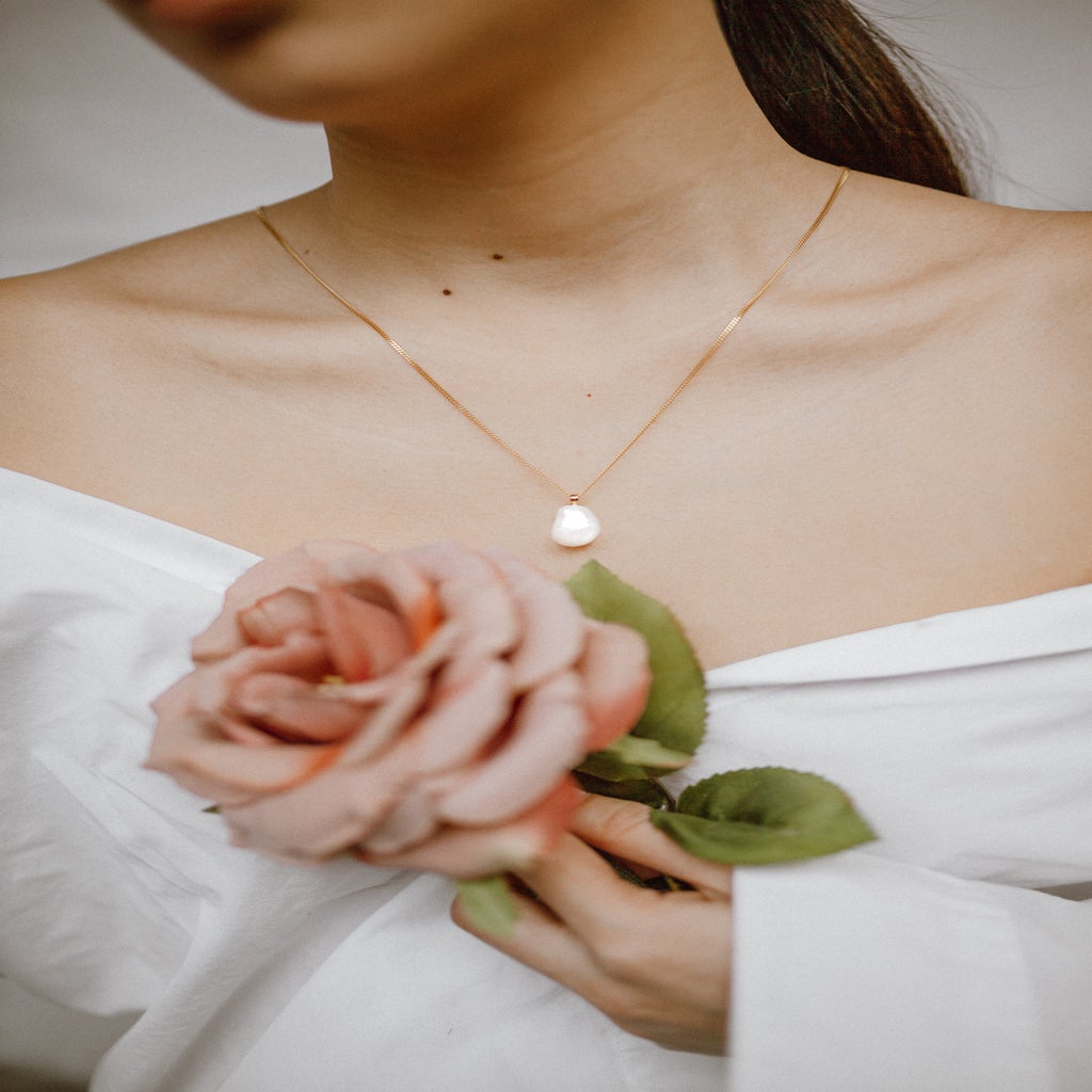 woman in white dress holding pink rose