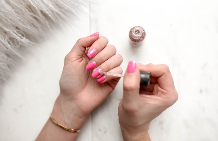 woman painting nails with pink polish