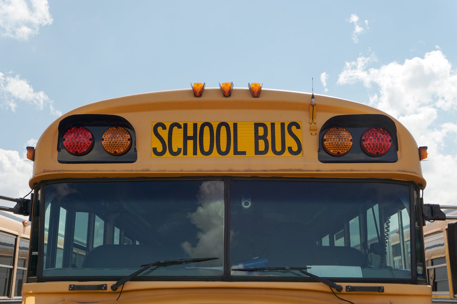 Front windshield and lights of a traditional yellow school bus.