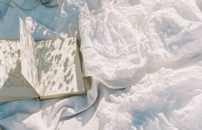 white flowers and open book on white sheets