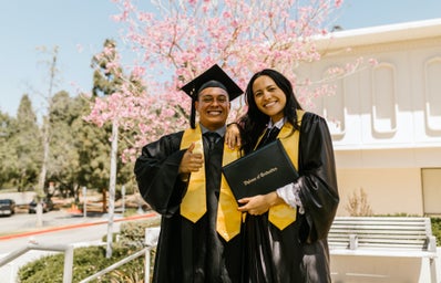 man and woman in graduation robes holding diploma