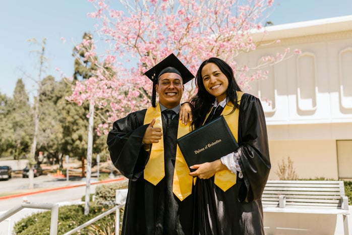 man and woman in graduation robes holding diploma