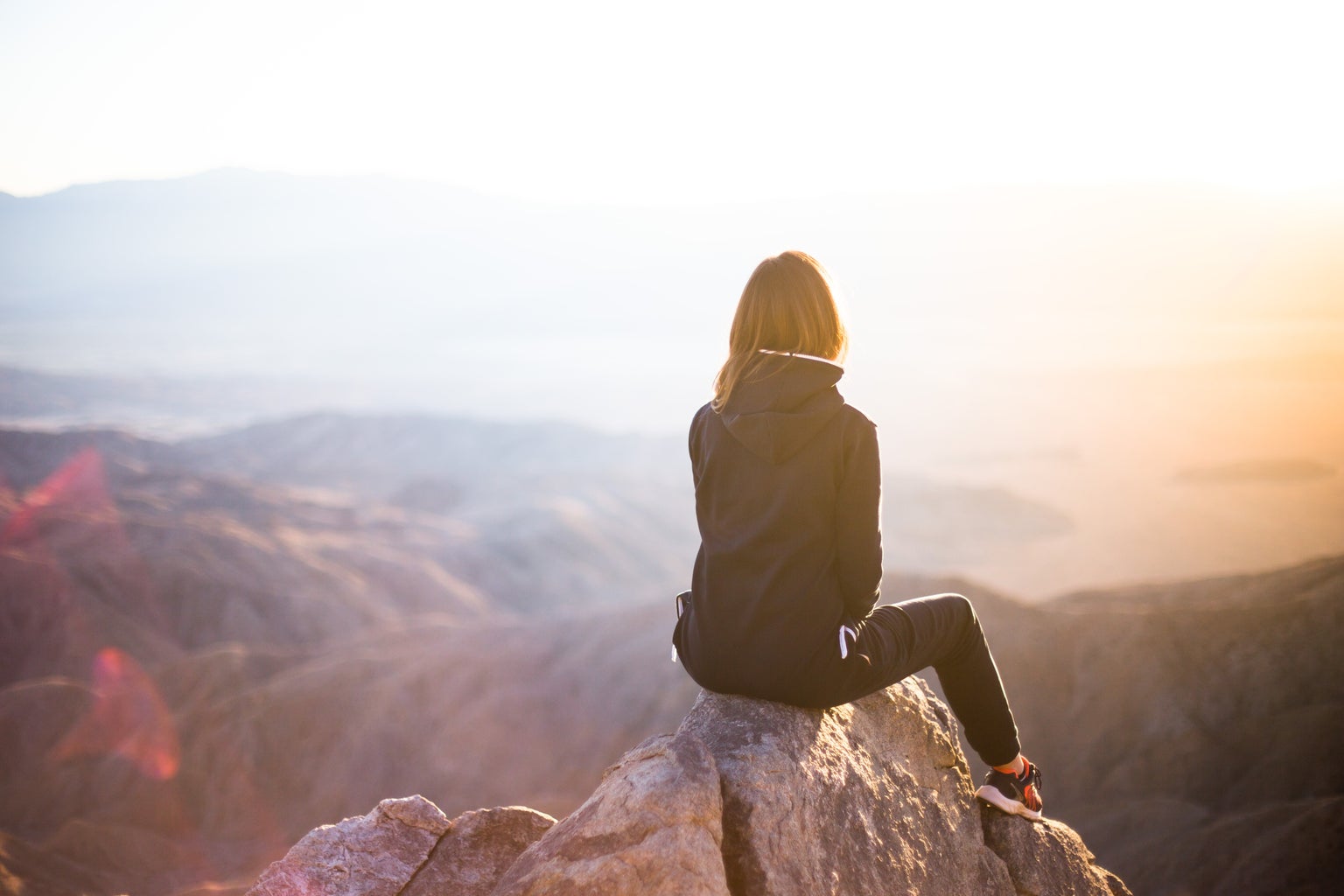 Woman sitting on a rock looking at the horizon.