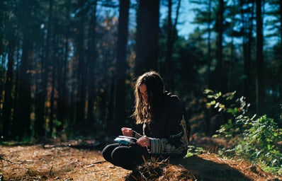 woman sitting in the forest writing