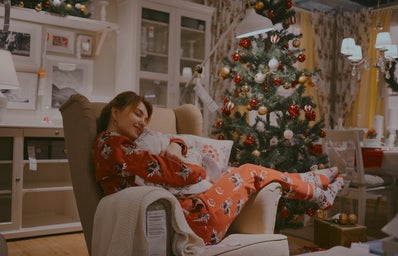 woman in pajamas hugging a pillow with christmas tree in background
